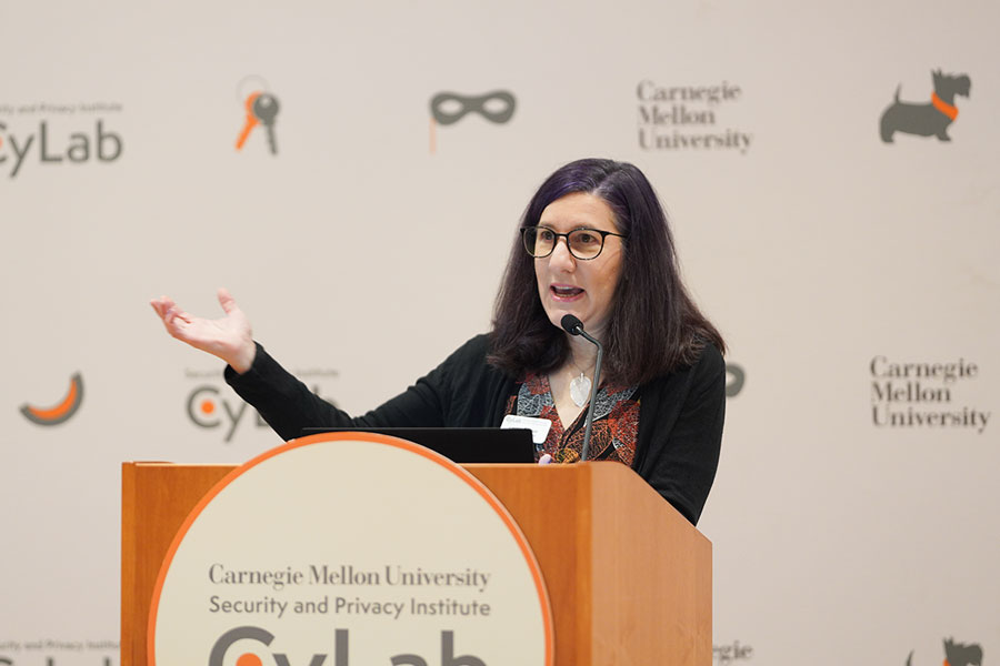 A woman stands at a podium, speaking.